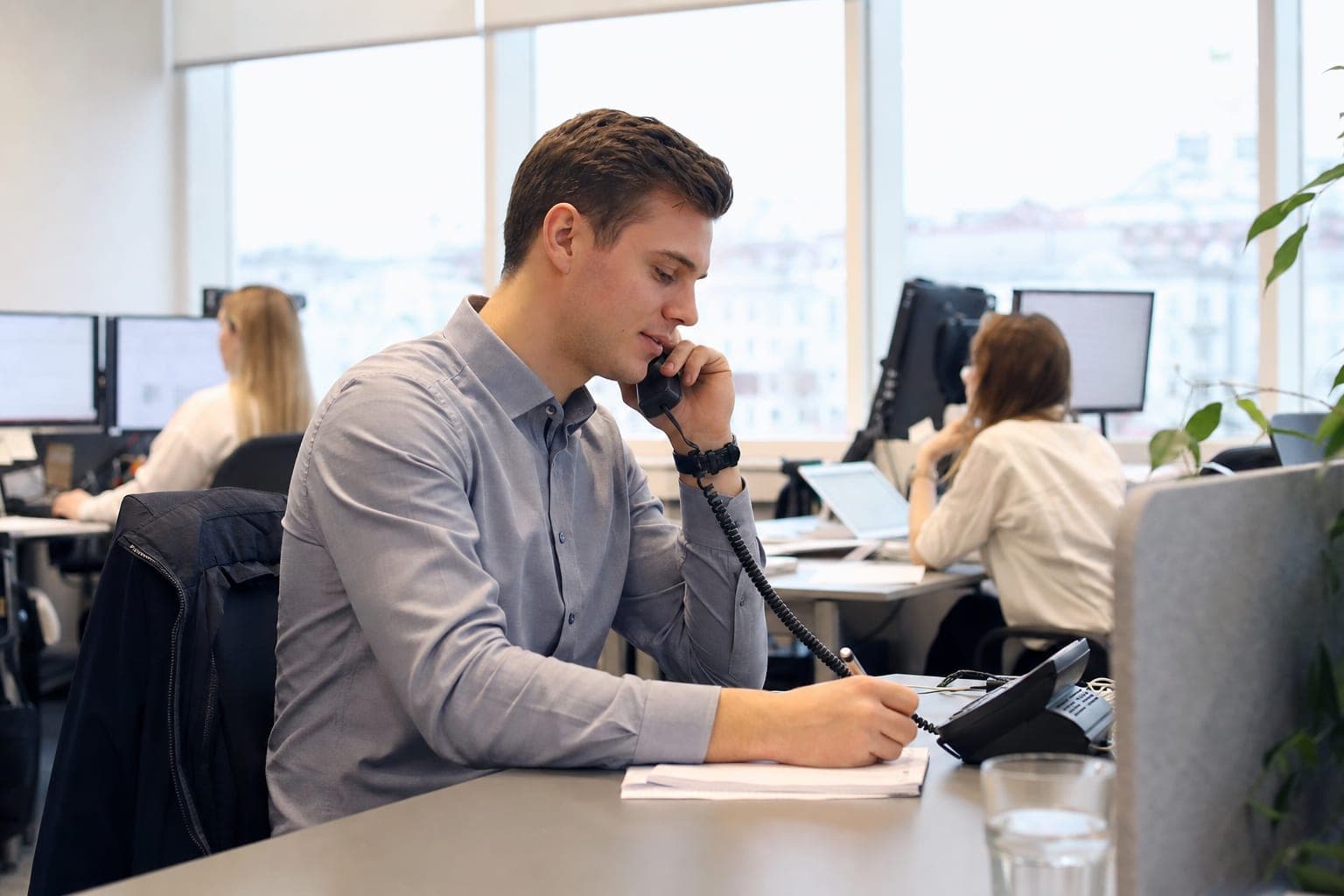 Recruiter im Büro am Telefon, daneben Notizblock und Tischapparat